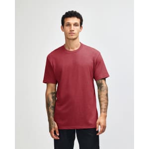 A unisex CVC short sleeve T-shirt in a rich burgundy colour, displayed on a model. Features a logo.