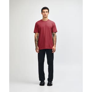 A maroon unisex CVC short sleeve t-shirt worn by a model, paired with black cargo pants. The model has a casual stance.