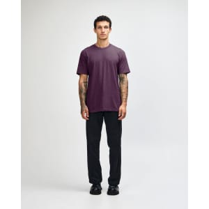 A unisex short sleeve T-shirt in a deep purple colour, paired with black cargo pants, featuring a logo.