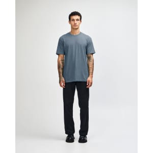 A short sleeve unisex t-shirt in a blue shade, paired with black cargo pants, featuring a logo.
