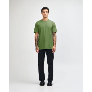 A model wearing a green unisex CVC short sleeve T-shirt paired with black cargo pants and sneakers.