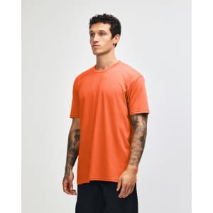 An orange unisex CVC short sleeve t-shirt displayed on a model, featuring a casual fit and a logo.