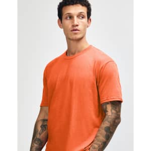 An orange unisex short sleeve T-shirt is displayed on a model with a neutral background. The shirt has a simple design and consists of soft fabric.