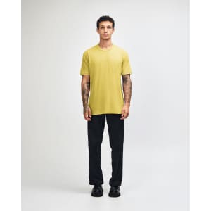 A unisex short sleeve t-shirt in yellow, paired with dark cargo pants and sneakers, worn by a standing model.