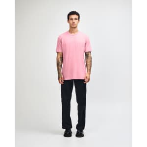 A model wearing a pink unisex CVC short sleeve t-shirt paired with dark cargo pants and trainers.