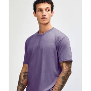 A unisex short sleeve t-shirt in a purple hue, featuring a simple design and a logo.