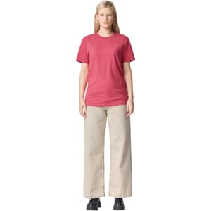 A unisex CVC short sleeve t-shirt in a berry shade, paired with light beige wide-leg trousers. The model stands straight, showcasing the outfit.