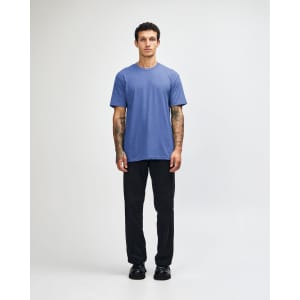 A unisex CVC short sleeve T-shirt in blue, paired with black cargo pants and casual footwear.
