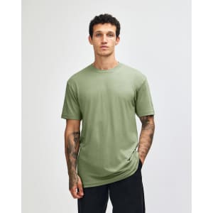 A plain green unisex CVC short sleeve T-shirt displayed on a model, featuring a subtle logo.