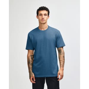 A unisex short sleeve t-shirt in a blue shade, displayed on a model with straight posture. Features a logo.