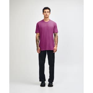 A unisex short sleeve T-shirt in vibrant pink, paired with relaxed black pants and a casual stance.