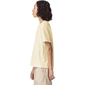 A side view of a youth t-shirt in pale yellow, featuring a relaxed fit and a logo.