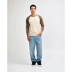 A unisex raglan T-shirt in cream with brown sleeves, paired with light blue cargo pants. Features a logo.