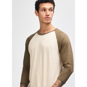A unisex raglan T-shirt featuring a beige body and brown sleeves, with a model displaying the shirt.