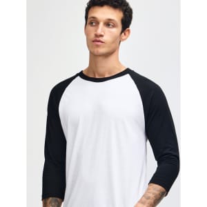 A unisex raglan T-shirt featuring black sleeves and a white body, worn by a model with a shaved head.