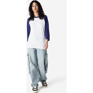 A unisex raglan T-shirt featuring white fabric with navy blue sleeves, worn with casual baggy pants.