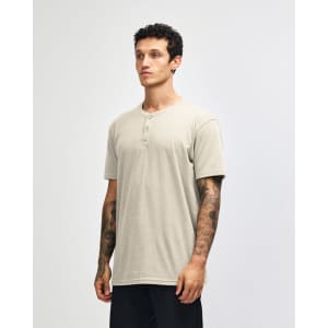 A unisex henley T-shirt in beige, featuring a round neckline and short sleeves, displayed on a model.