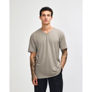 A unisex V-neck T-shirt in a muted beige colour with short sleeves and a relaxed fit. It features a logo on the garment.