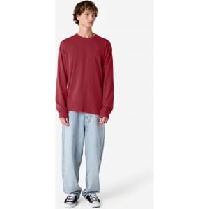 A long sleeve T-shirt in red, paired with light blue baggy jeans and black sneakers, featuring a logo.