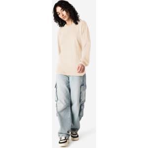 A beige long sleeve t-shirt paired with light blue cargo pants, featuring a logo on the shirt.