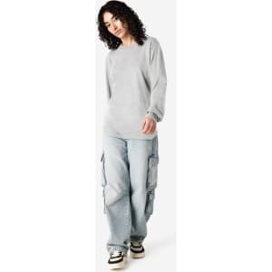 A model wears a grey American Apparel long sleeve T-shirt with loose-fitting cargo jeans. The image features branding.