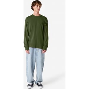 A long sleeve t-shirt in olive green, displayed on a model wearing loose-fitting light denim jeans and black sneakers.