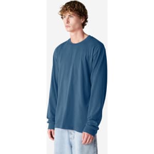 A long sleeve t-shirt in a blue colour, featuring a logo, worn by a model standing sideways.