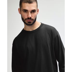 A model wearing a black long sleeve t-shirt made of ultra cotton, featuring a simple design and relaxed fit.