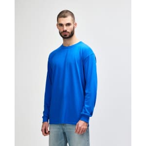 A long-sleeve T-shirt in bright blue, featuring a logo, worn by a model facing left.