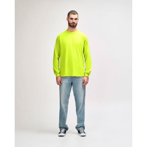 A model wearing a bright yellow long sleeve T-shirt paired with black jeans and sneakers, featuring a logo.
