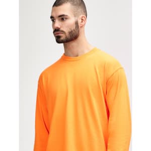 An orange long sleeve T-shirt on a model, featuring a simple design and a logo on the shirt.