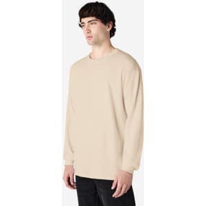 A beige long sleeve T-shirt on a model, featuring a simple design and a logo on the garment.