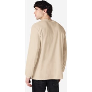 A man wearing a beige Gildan Ultra Cotton long sleeve T-shirt, viewed from the back. The shirt features a logo.