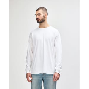 A white long sleeve T-shirt displayed on a model, featuring a round neckline and a logo on the sleeve.