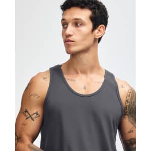 A unisex fine jersey tank in grey, featuring wide armholes and a simple design. The model is adjusting the tank.