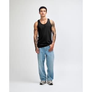 A black unisex fine jersey tank top worn with baggy black pants and sneakers, featuring a visible logo.