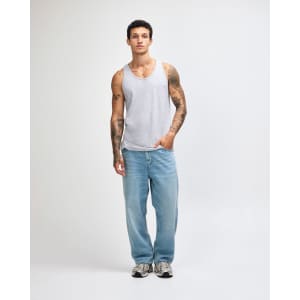 A unisex fine jersey tank in grey, paired with loose-fitting light blue jeans and black shoes. Features a logo.