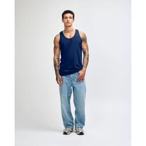 A model wearing a navy blue unisex fine jersey tank top paired with black cargo pants and sneakers.
