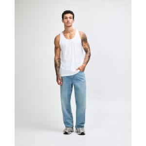 A model wearing a white unisex fine jersey tank top paired with dark cargo pants and sneakers.