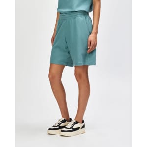 Unisex gym shorts in teal with pockets and a drawstring waistband, worn with white sneakers and socks.