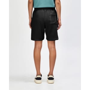 Unisex pique gym shorts in black, featuring an elastic waistband and side pockets, worn with black sneakers and white socks.