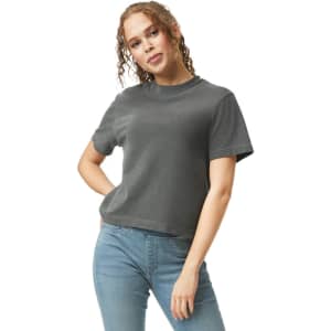 A woman is wearing a dark grey boxy t-shirt paired with blue jeans, with curly hair framing her face.