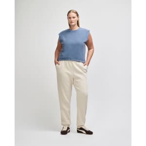 A navy blue women's muscle t-shirt is paired with light blue baggy jeans. The model stands in a neutral setting.
