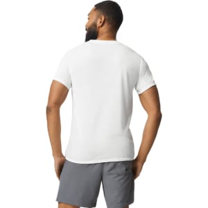 A man wearing a white Gildan Performance adult t-shirt, viewed from the back, paired with grey shorts.