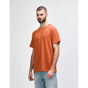 A plain orange adult t-shirt featuring a round neck and short sleeves, displayed on a model.