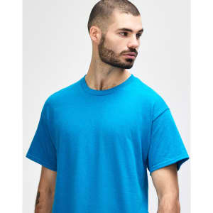 A blue Gildan Heavy Cotton adult t-shirt on a male model, featuring a plain design and a logo.