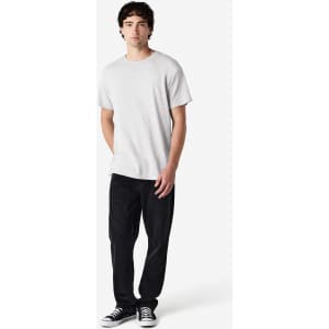A light grey Gildan Heavy Cotton adult T-shirt worn with black pants and casual shoes, featuring a logo.