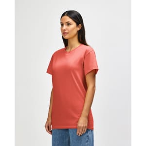 A model wearing a coral Gildan Heavy Cotton Adult T-Shirt, paired with light blue jeans. The shirt has a logo.