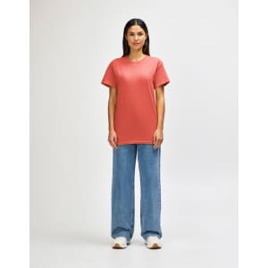 A model wearing a coral Gildan Heavy Cotton Adult T-Shirt paired with light blue jeans and white shoes.