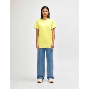 A man wearing a bright yellow Gildan Heavy Cotton adult T-shirt paired with blue jeans. The shirt has a logo.